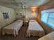 Bedroom featuring two twin beds, wood paneling, and a ceiling fan at 808 53Rd E Ave # 234, Bradenton, FL 34203