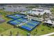 Aerial view of community tennis and pickleball courts and clubhouse with pool in tropical landscape at 8722 Backshore Ln, Parrish, FL 34219