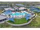 Aerial view of community center with expansive pool area, blue sunshades, palm trees and manicured lawn at 8722 Backshore Ln, Parrish, FL 34219