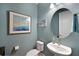 Half bathroom with a wall sink, a round mirror, and elegant wall art at 8722 Backshore Ln, Parrish, FL 34219