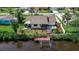 Aerial view of backyard featuring a dock with water access, screened-in lanai, and lush landscaping at 9011 Hilolo Ln, Venice, FL 34293