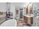 Stylish bathroom featuring wood plank tile, a claw foot tub, double sink vanity, and glass enclosed shower at 9011 Hilolo Ln, Venice, FL 34293