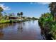 Picturesque canal view featuring waterfront properties and docks, surrounded by lush greenery and palm trees under a clear sky at 9011 Hilolo Ln, Venice, FL 34293