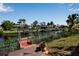 Waterfront property with a private wooden dock and boat lift on a canal with lush tropical landscaping at 9011 Hilolo Ln, Venice, FL 34293