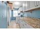 Bright laundry room featuring blue walls, tile floors, washer/dryer, granite counters and ample cabinet space at 9011 Hilolo Ln, Venice, FL 34293
