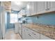 Bright laundry room featuring blue walls, tile floors, washer/dryer, granite counters and ample cabinet space at 9011 Hilolo Ln, Venice, FL 34293