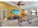 Inviting living room featuring a large sectional sofa, entertainment center, and ceiling fan at 9011 Hilolo Ln, Venice, FL 34293