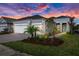 Beautiful single-story home with a two car garage, lush landscaping and a paver driveway at sunset at 10217 Canaveral Cir, Sarasota, FL 34241