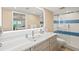 Bright bathroom with modern vanity, sink, and a glass-enclosed shower with blue tile accents at 1050 Longboat Club Road # 903, Longboat Key, FL 34228