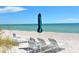 Beach chairs and umbrella on a white sandy beach with the ocean and blue sky in the background on a clear and sunny day at 1050 Longboat Club Road # 903, Longboat Key, FL 34228