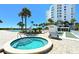 Hot tub next to a shuffleboard court and community pool with a white high-rise building on a clear and sunny day at 1050 Longboat Club Road # 903, Longboat Key, FL 34228