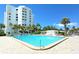Wide angle view of a large community pool next to a white high-rise building on a clear and sunny day at 1050 Longboat Club Road # 903, Longboat Key, FL 34228