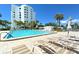 A lounge chair next to a community pool with a white high-rise building in the background on a clear and sunny day at 1050 Longboat Club Road # 903, Longboat Key, FL 34228