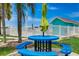 Outdoor dining area with blue picnic table, umbrella, palm tree, and white fenced pool at 117 7Th N St # 5, Bradenton Beach, FL 34217