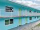 Clean exterior view of two-story blue condo featuring a metal safety rail balcony and pastel green doors at 117 7Th N St # 5, Bradenton Beach, FL 34217