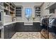 Well-lit laundry room with gray cabinets, white countertops, farmhouse sink, open shelving, and high-end washer and dryer at 12615 River Rd, Myakka City, FL 34251