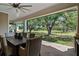 Covered outdoor patio featuring wood floors, brick columns, dining table, and expansive views of landscaped backyard at 12615 River Rd, Myakka City, FL 34251