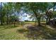 Scenic property entrance with a wooden gate, leading to a beautiful grassy field and wooded area at 12615 River Rd, Myakka City, FL 34251