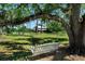 Relaxing white wooden tree swing hanging from a mature tree on a lush green lawn at 12615 River Rd, Myakka City, FL 34251