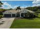 Charming home with a paver driveway, three-car garage, lush landscaping, and arched entry at 12810 Magpie Pl, Bradenton, FL 34212