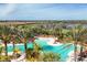 Stunning community pool surrounded by lounge chairs, palm trees, and lush landscaping with blue sky at 13902 Messina Loop, Bradenton, FL 34211