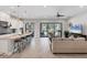 Bright living room with an open floor plan leading to an outdoor patio and modern kitchen with bar seating at 13902 Messina Loop, Bradenton, FL 34211