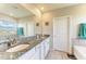 Bathroom featuring double sinks with granite countertops, a large mirror, and a tub at 17669 Cantarina Cv, Bradenton, FL 34211