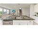 Modern kitchen features a speckled granite countertop, stainless steel sink, and view into the living area at 17669 Cantarina Cv, Bradenton, FL 34211