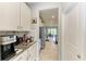 Galley kitchen featuring white cabinets, stainless steel appliances, and convenient access to dining area at 17669 Cantarina Cv, Bradenton, FL 34211