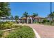 Community clubhouse entrance with manicured landscaping and palm trees at 23572 Awabuki Dr # 202, Venice, FL 34293