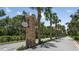Community entrance sign amidst lush landscaping and palm trees on a sunny day at 23819 Collina Way # 102, Port Charlotte, FL 33980