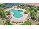 Aerial view of the cloverleaf shaped pool surrounded by brick pavers, lounge chairs, and tropical landscaping at 23819 Collina Way # 102, Port Charlotte, FL 33980