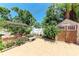 Charming backyard featuring a brick-paved patio, a stone bench, colorful flowers, and a wooden shed at 3053 Monica Pkwy, Sarasota, FL 34234