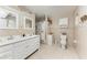 Well-lit bathroom with double vanity, tile flooring, and shower with floral curtain at 3053 Monica Pkwy, Sarasota, FL 34234