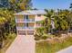 Three-story home featuring private balconies, a paver driveway, two-car garage, and mature landscaping at 306 Poinsettia Rd, Anna Maria, FL 34216
