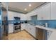 A modern kitchen is equipped with stainless steel appliances, white cabinets, and beautiful blue backsplash at 306 Poinsettia Rd, Anna Maria, FL 34216
