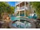 Outdoor pool with jacuzzi and rock waterfall in backyard surrounded by lush tropical trees at 306 Poinsettia Rd, Anna Maria, FL 34216