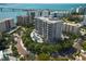 Stunning aerial view of modern condo building with pool, lush landscaping, and bay views at 325 Golden Gate Pt # 1004, Sarasota, FL 34236