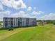 Exterior elevation of multi-story condo building overlooking green space and pool at 3790 Pinebrook Cir # 408, Bradenton, FL 34209