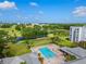 Aerial view of a community pool, set among lush greenery, a golf course, and sunny skies at 3790 Pinebrook Cir # 408, Bradenton, FL 34209