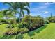 Tropical landscaping surrounds this backyard, lush green lawn, and mature palm trees at 405 Park N Blvd, Venice, FL 34285