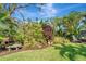 Backyard featuring lush landscaping, mature trees, a bench and outdoor seating, and a well-manicured lawn at 405 Park N Blvd, Venice, FL 34285
