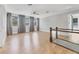 Large loft space with wood flooring, multiple windows with gray drapes, and glass-paneled banister at 4112 Swift Rd, Sarasota, FL 34231