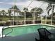 Inviting screened-in pool area with views of the lush green golf course and mature palm trees at 5449 Downham Mdws, Sarasota, FL 34235