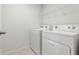 Functional laundry room with white washer and dryer, wire shelving, and neutral-toned tile flooring at 5543 Pleasantview Ct, Bradenton, FL 34211