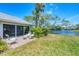 Back patio seating area with sliding glass doors overlooking the lush lawn and a peaceful pond at 5578 Country Club Way, Sarasota, FL 34243