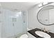 Modern bathroom with a glass shower, sleek vanity, and a large round mirror, exuding contemporary style at 5663 Midnight Pass Rd # 407, Sarasota, FL 34242