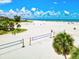 Expansive white sand beach with volleyball nets and palm trees under a sunny blue sky at 5663 Midnight Pass Rd # 407, Sarasota, FL 34242