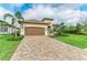 Beautiful home showcasing a two-car garage, paver driveway, manicured lawn, and vibrant tropical landscaping at 5810 Brandon Run, Bradenton, FL 34211