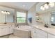 Bright main bathroom with a large soaking tub, double vanity, and granite countertops at 5810 Brandon Run, Bradenton, FL 34211
